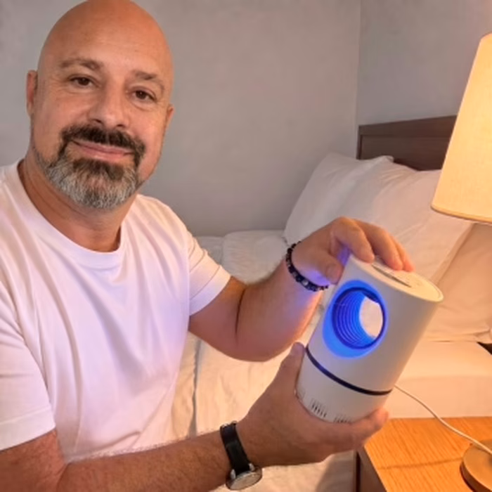 Utilisateur présentant la lampe ZapiTrap posée sur sa table de nuit