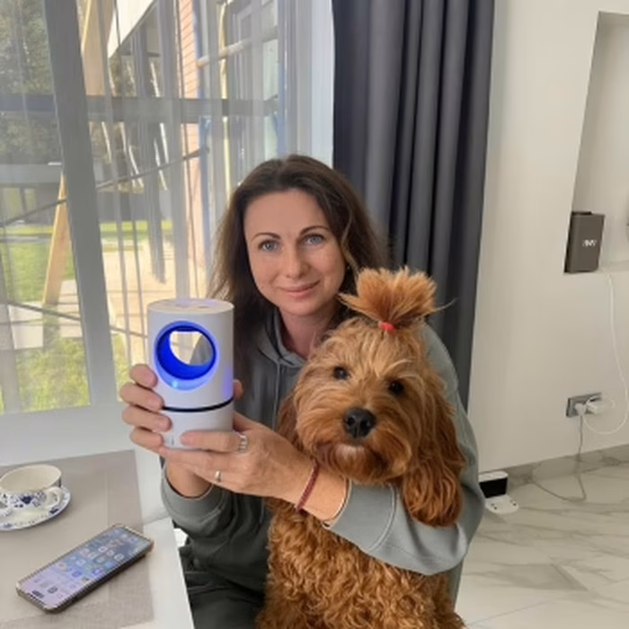 Utilisatrice tenant la lampe ZapiTrap à côté de son chien dans le salon